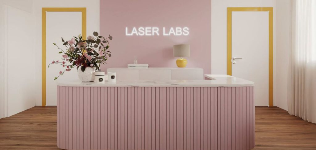 Empfangsbereich eines Laser-Haarentfernungsstudios in Graz mit stilvoller rosa Theke, dekorativen Blumen und modernem Interieur