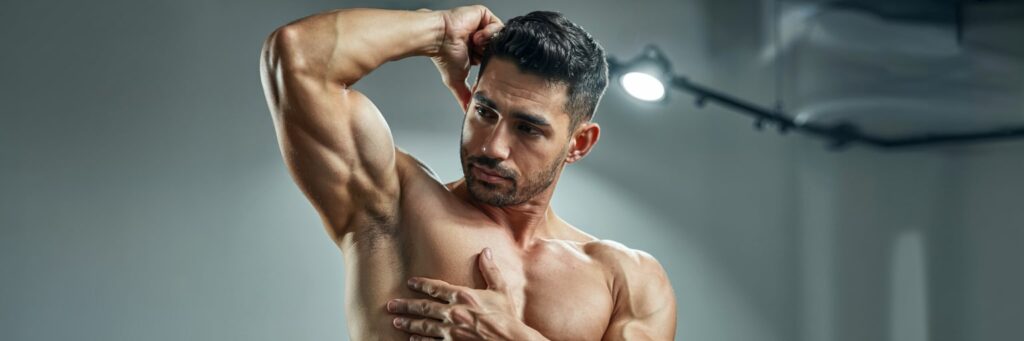 Muskulöser Mann präsentiert seine glatte, haarfreie Haut und definierten Oberkörper in einem hellen Fitnessstudio. - Sitzungen