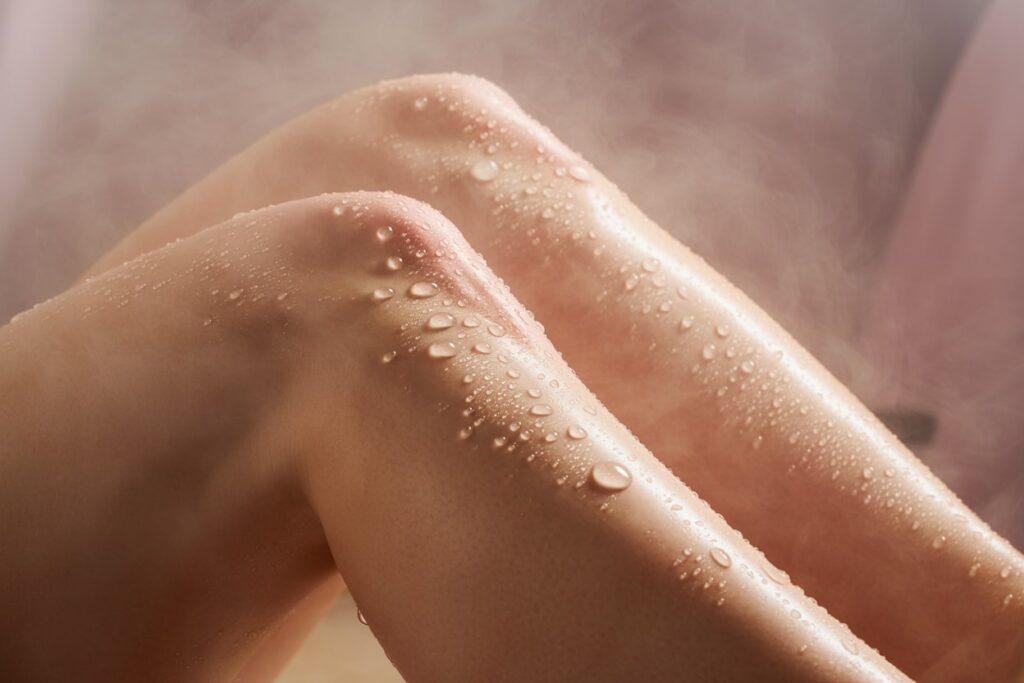 Frisch gepflegte Frauenbeine mit Wassertropfen – Sinnbild für Hautpflege nach dem Lasern.